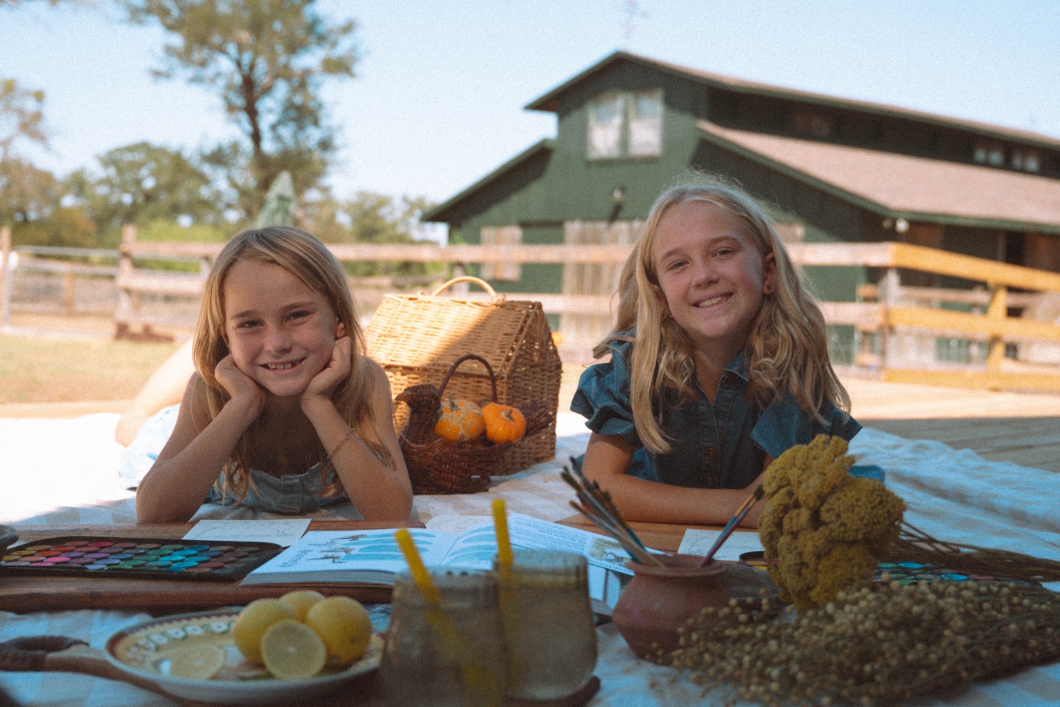 Two girls sitting at an outdoor art table at Feral Farmstead