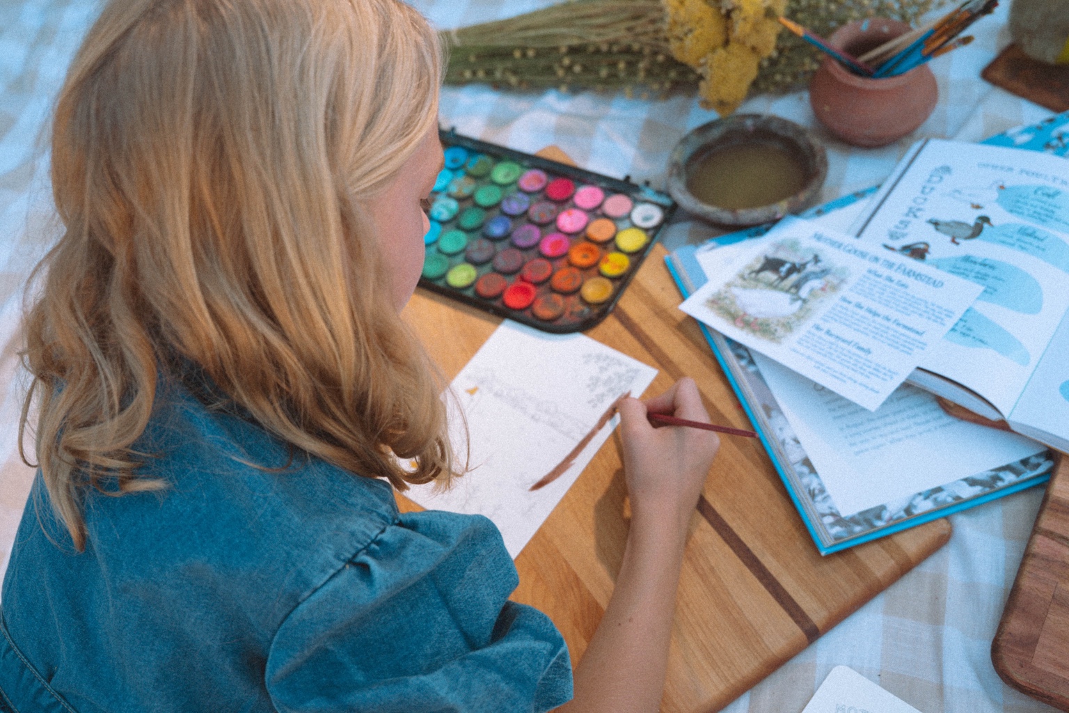 A child painting a Mother Goose watercolor page